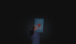 Man holding a closed LoveBook at arm's length